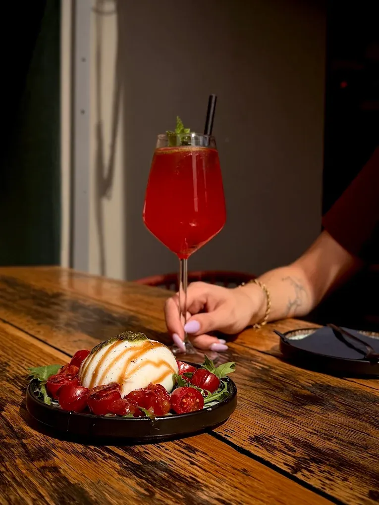Burrata met geroosterde tomaatjes en een rode spritz op een houten tafel