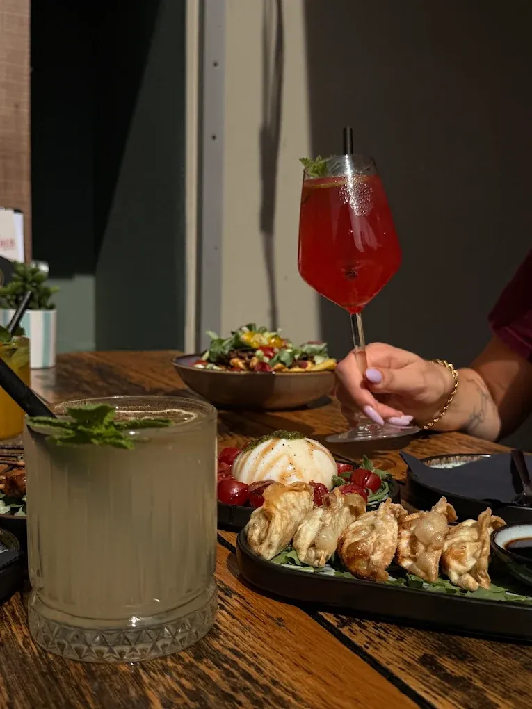 Een rode spritz, limonade met munt, burrata en gyoza’s op tafel